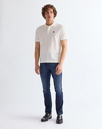 Ganzkörperaufnahme eines Mannes im weißen Poloshirt und dunkler Jeans